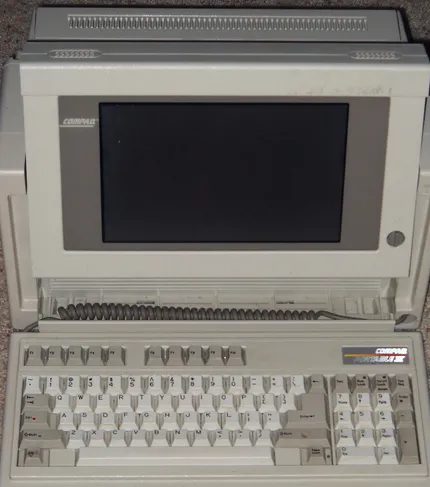 A Compaq Portable III luggable, open: a dark gas-plasma screen above a fold-down keyboard.